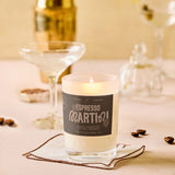Candle labeled 'Espresso Martini' on a table with coffee beans and glasses in the background